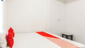 A simple room with a bed, a small table, and a wall socket. - Hotel O Kawi Homestay (Praya Barat Daya)