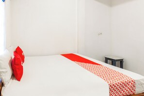 A simple room with a bed, a small table, and a wall socket. - Hotel O Kawi Homestay (Praya Barat Daya)