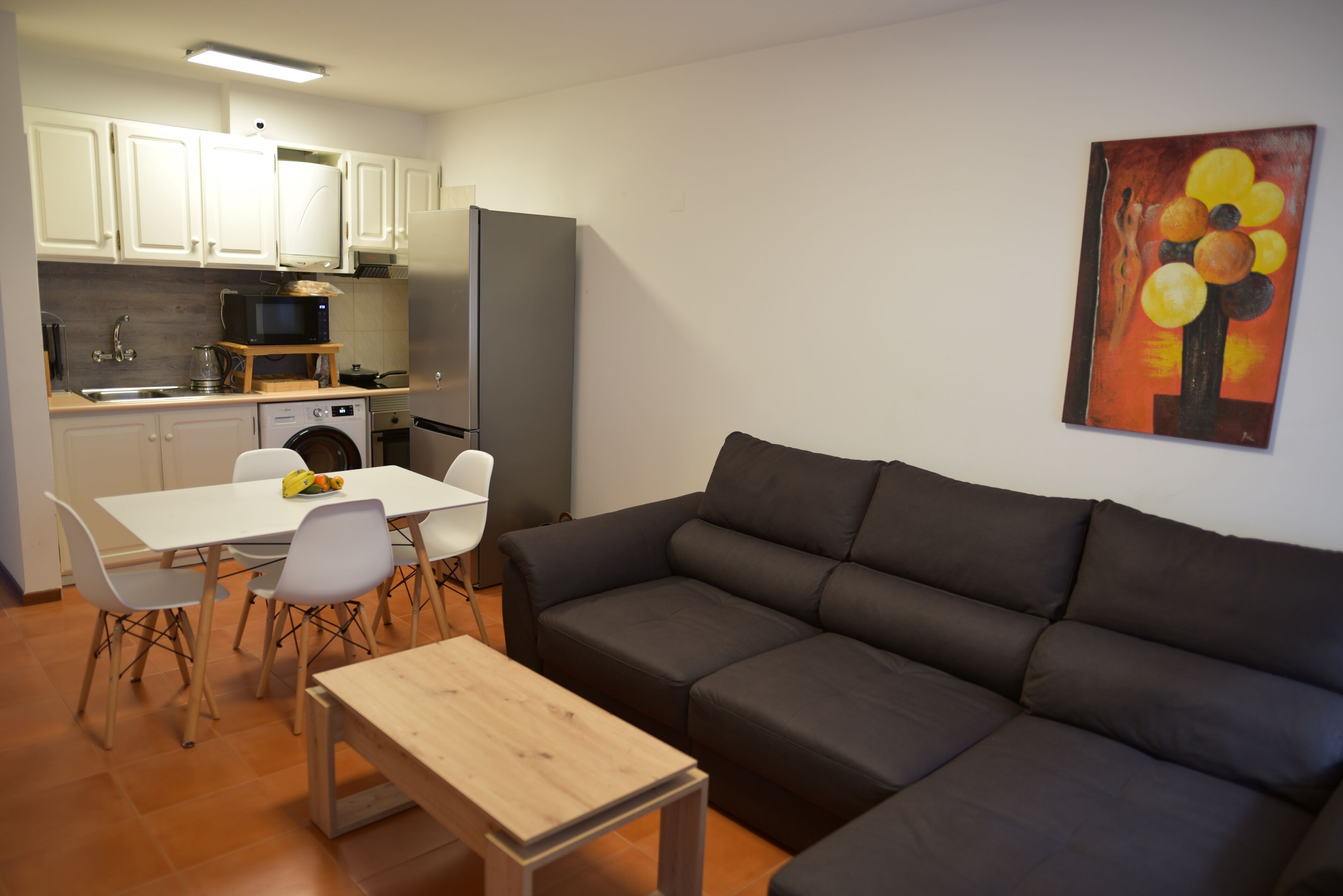 Un espacio habitable compacto con kitchenette, comedor y sofá.