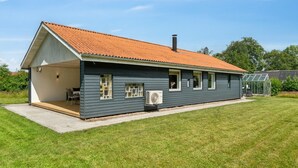 A modern house with a sloped roof, a covered patio, and a large window.