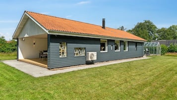 Une maison moderne avec un toit en pente, un patio couvert et une grande fenêtre.