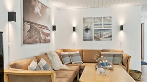 A modern living room with a beige sofa, a wooden coffee table, and wall-mounted lights.