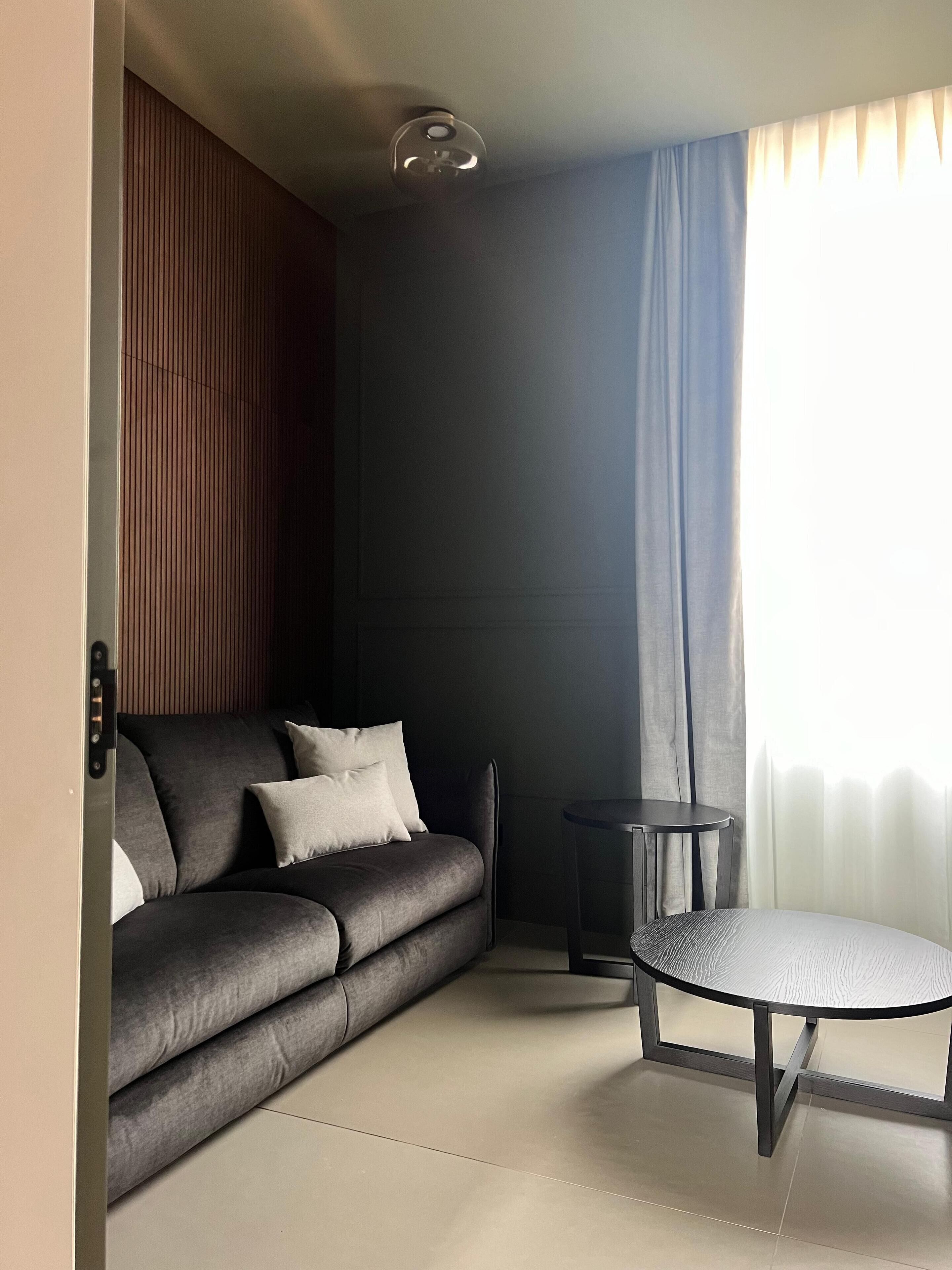 Een moderne woonkamer met een bank, een ronde tafel en een plafondlamp.