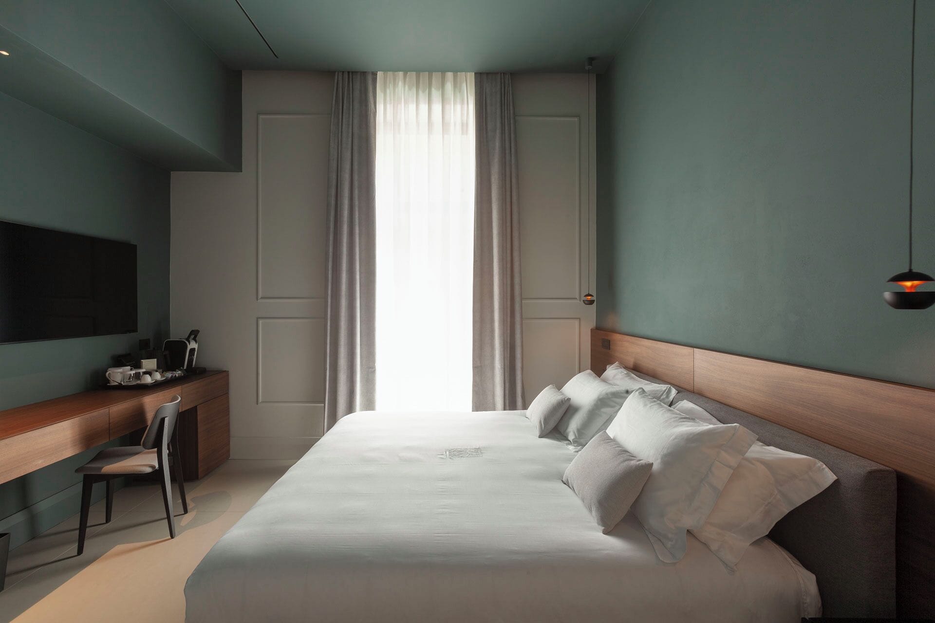 Une chambre d’hôtel moderne, dotée d’un grand lit, d’un bureau et d’une télévision.