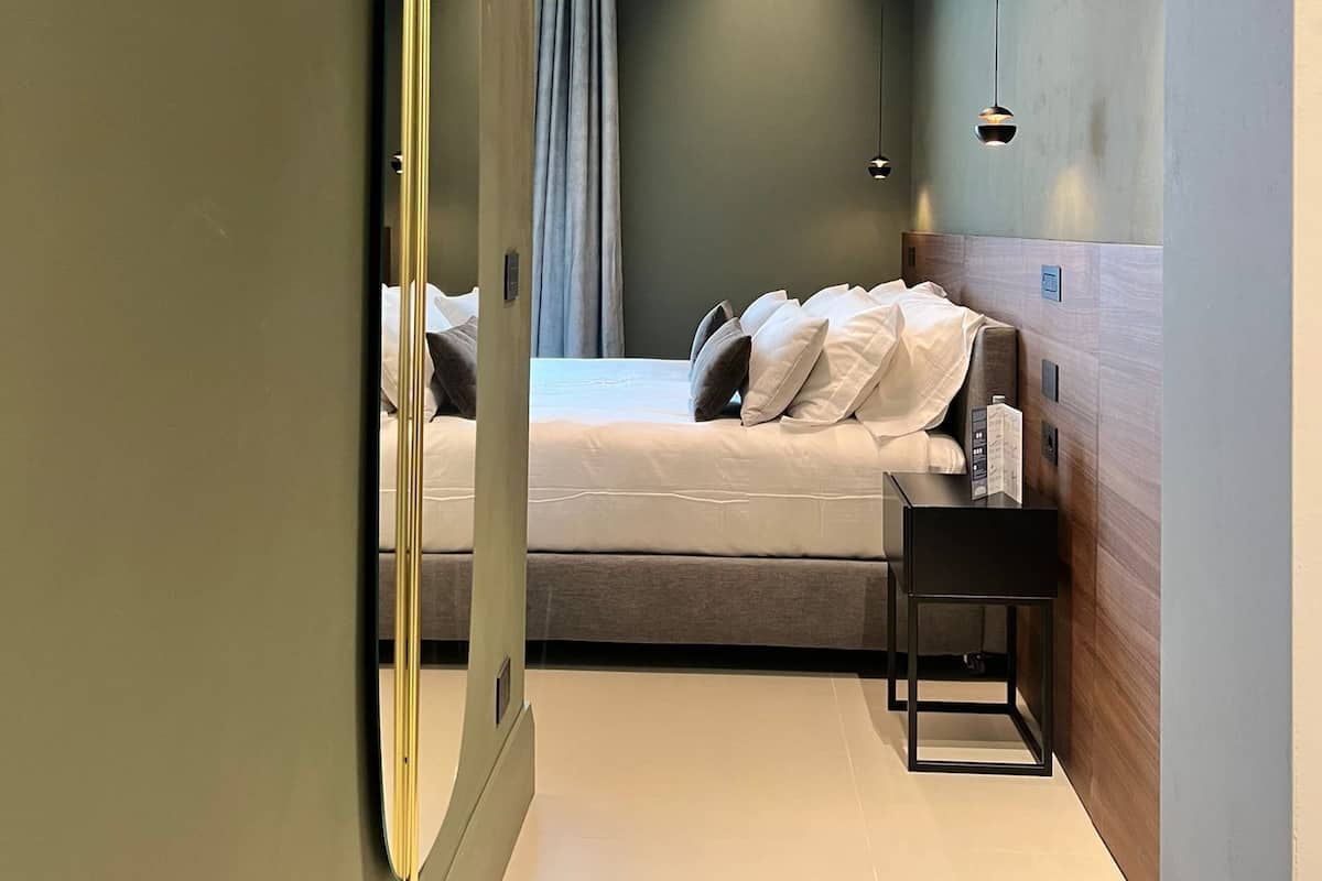 Una habitación de hotel moderna con una cama, una mesita de noche y un espejo.