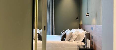 Ein modernes Hotelzimmer mit Bett, Nachttisch und Spiegel.