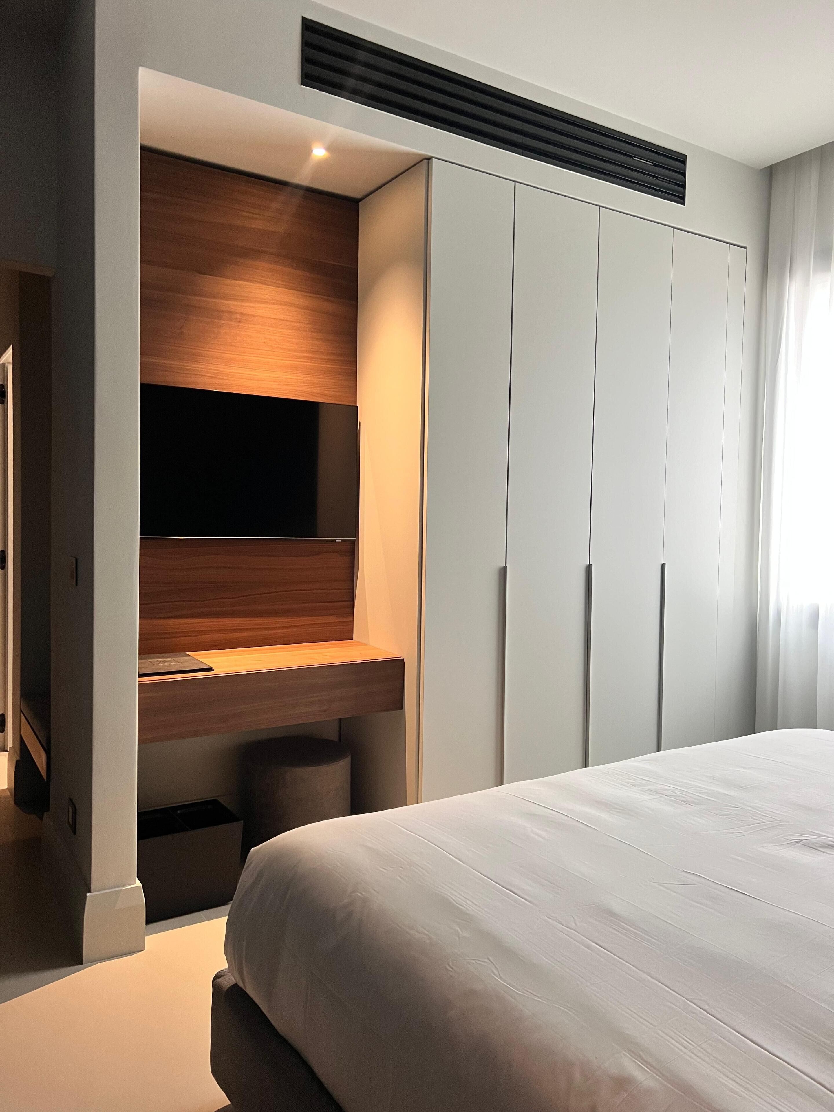 Ein Schlafzimmer mit Bett, integriertem Fernseher und Kleiderschrank.