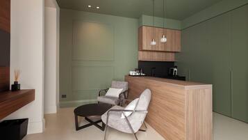 Una cocina moderna con una isla de madera, dos sillas grises y una cafetera negra.