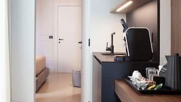 A modern kitchen with a built-in oven, a coffee machine, and a small seating area with a sofa and a round table.