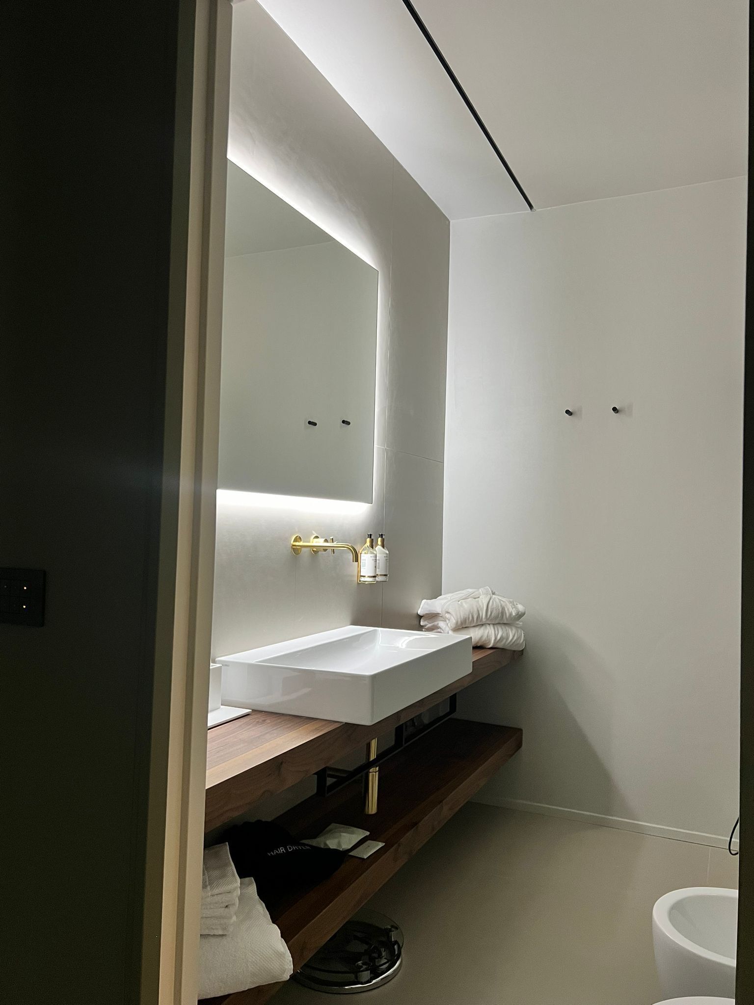 A modern bathroom with a white sink, a mirror, and a towel rack.