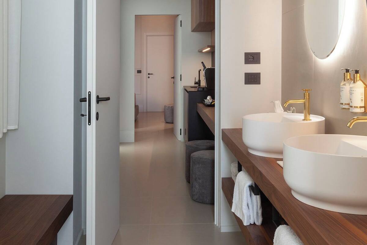 Un baño moderno con dos lavamanos, un espejo grande y una zona de ducha.
