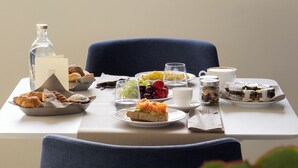 A dining table with a variety of food items and a bottle, set against a view of buildings and a plant. - Palazzo Giusti Lecce - Exclusive Boutique Hotel (Lecce)