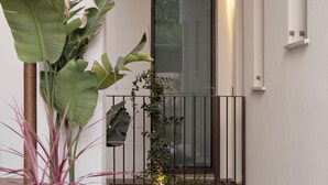 A modern building with a glass door, a small balcony with a metal railing, and potted plants. - Palazzo Giusti Lecce - Exclusive Boutique Hotel (Lecce)