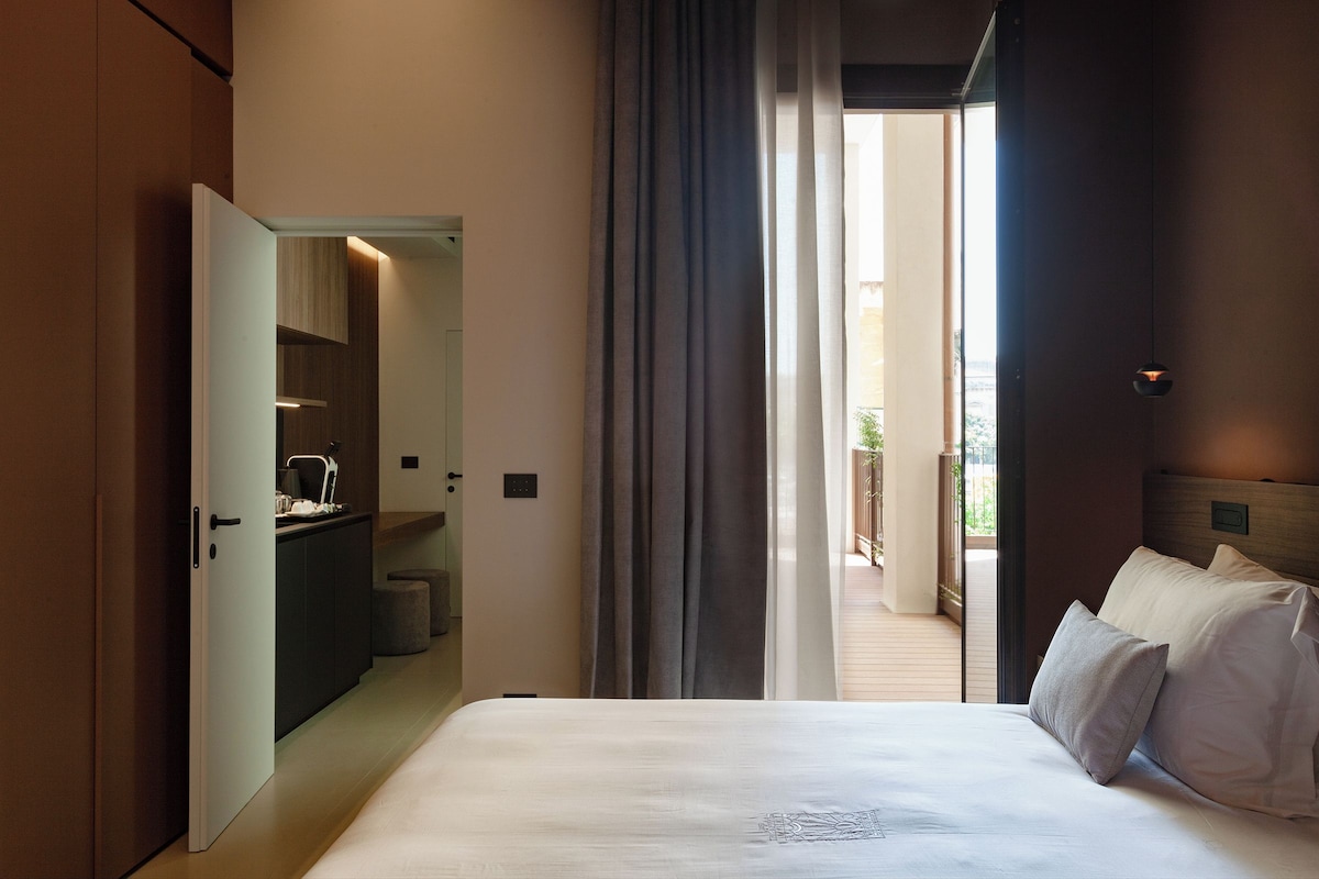 A hotel room with a bed, a bathroom, and a view of the outdoors.