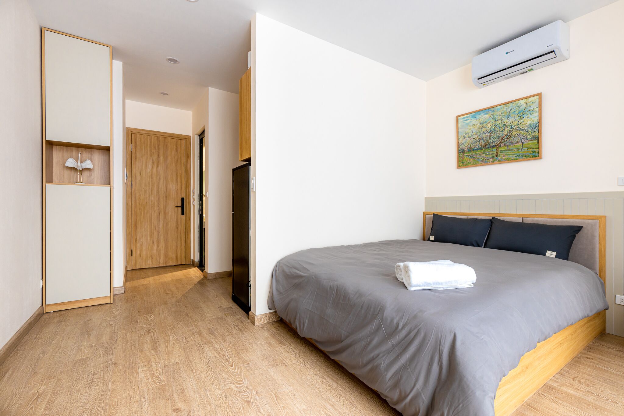 Una habitación de hotel con cama, armario, puerta y aire acondicionado.
