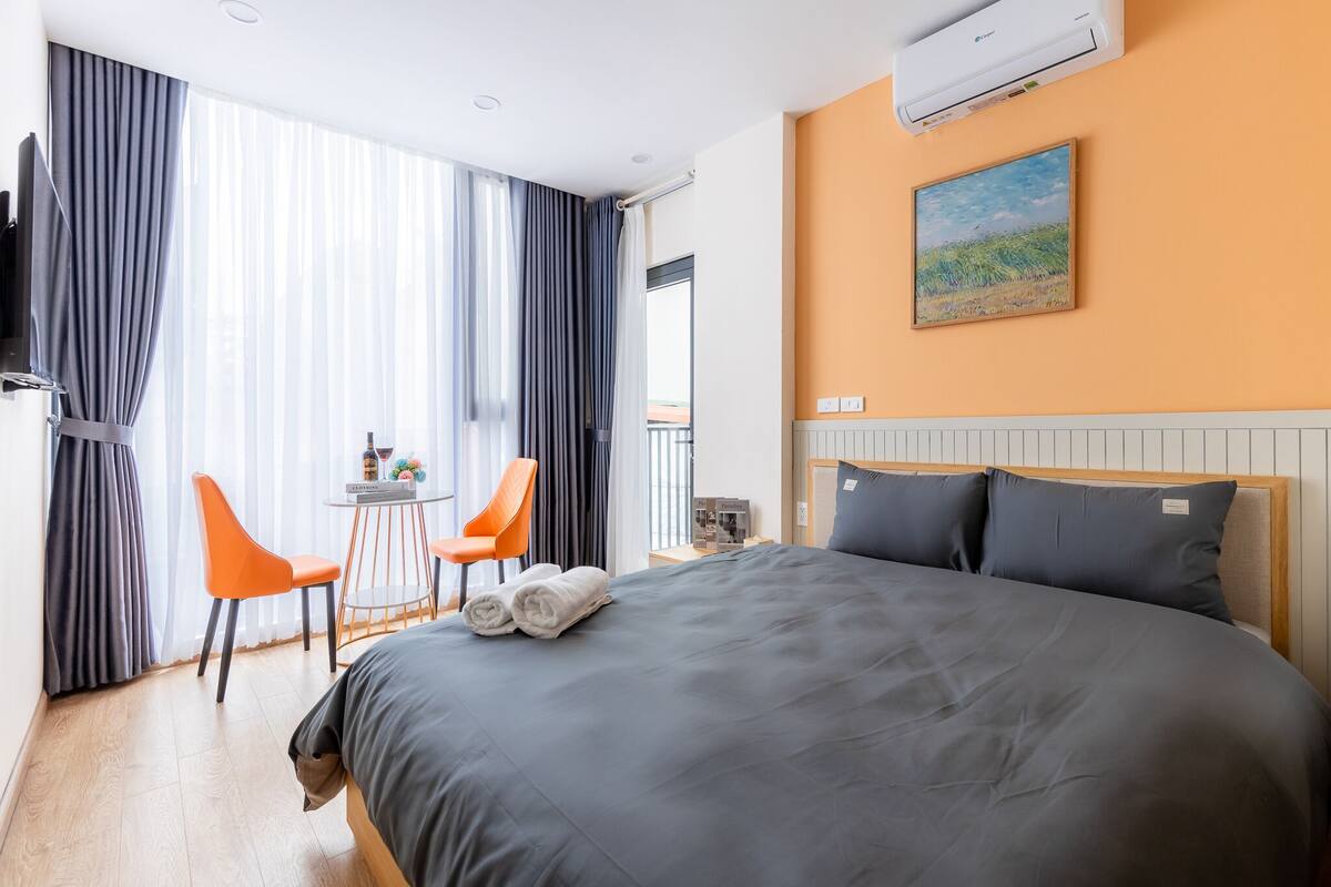 A hotel room with a large bed, a desk with a chair, a TV, and a painting on the wall.
