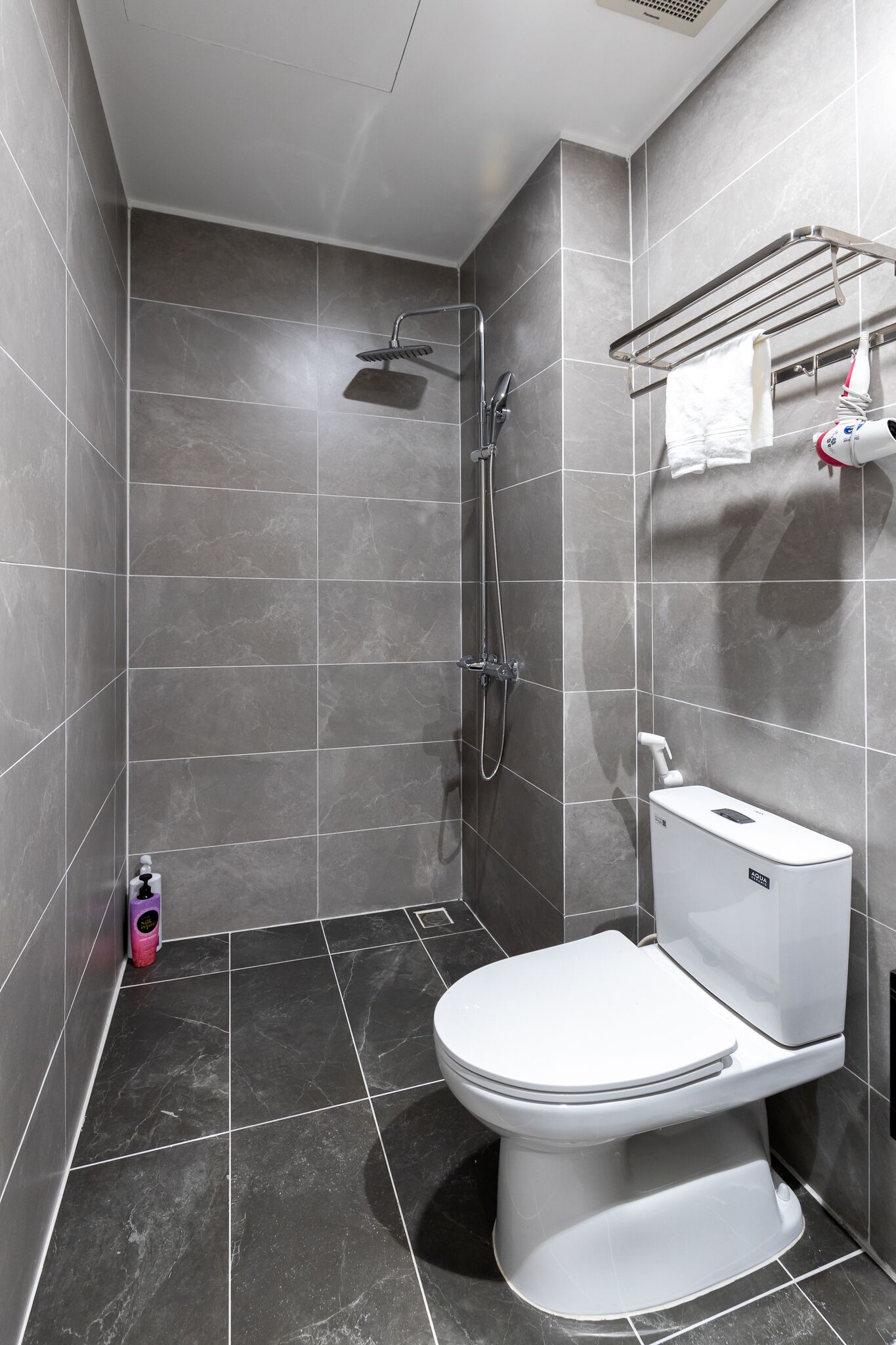 A modern bathroom with a shower, toilet, and a towel rack.