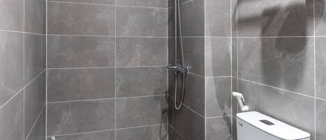 A modern bathroom with a shower, toilet, and a towel rack.