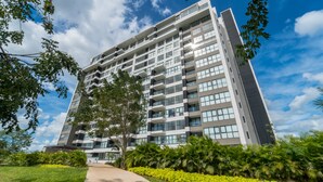 A modern multi-story building with balconies, surrounded by greenery and a clear sky. - Tower Indico by Casago (Mérida)