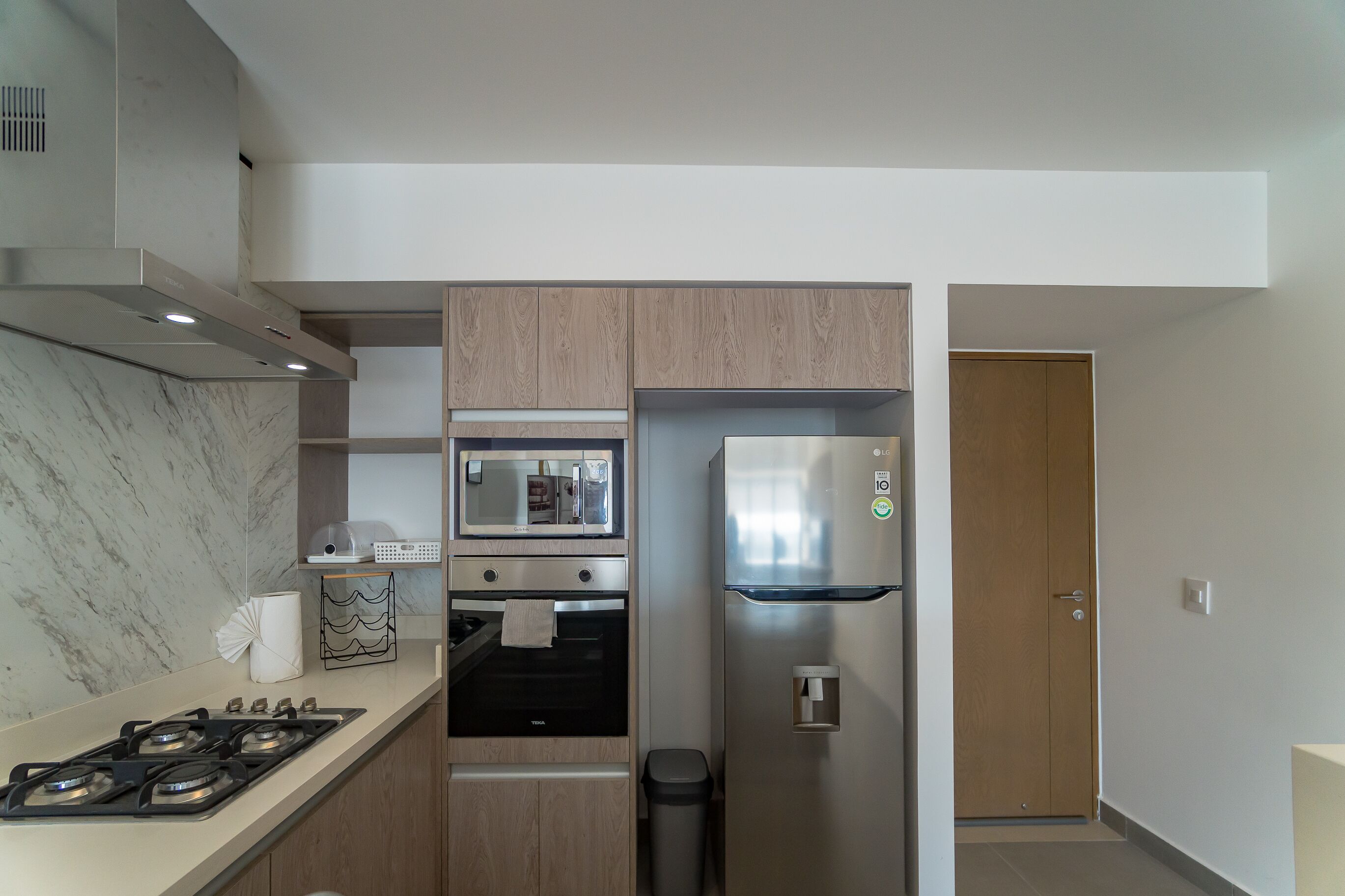 A compact kitchen with a gas stove, oven, microwave, and stainless steel refrigerator.