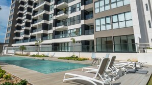 A modern hotel with multiple balconies, a swimming pool, and sun loungers. - Tower Indico by Casago (Mérida)