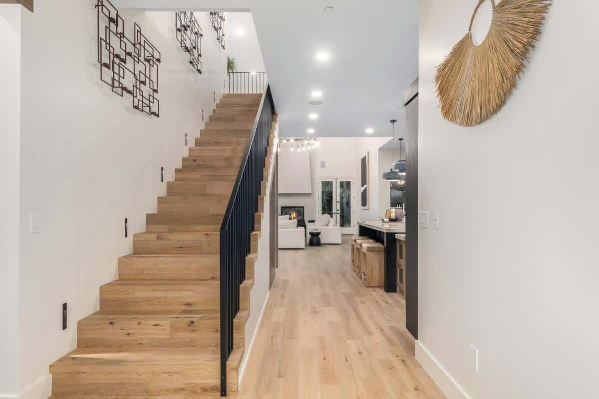 Un interior moderno con una escalera de madera, una zona de cocina y un espacio para comer.