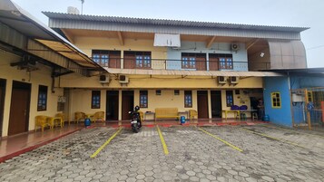 Un edificio con varias habitaciones, un espacio de descanso techado al aire libre y una motocicleta estacionada adelante.