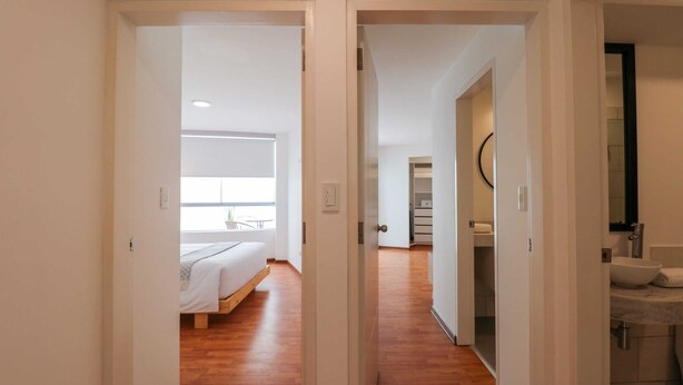 Une chambre d’hôtel avec un lit, une fenêtre et une salle de bain équipée d’un lavabo et d’un miroir.