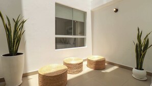 Un intérieur moderne avec une grande fenêtre, trois poufs en osier et deux plantes en pot.
