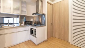 A modern kitchen with white cabinets, stainless steel appliances, and a wooden floor. - w* | Cozy Loft in Laureles (Medellín)
