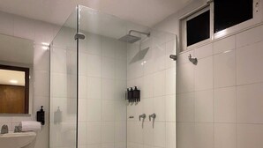 Un baño moderno con ducha acristalada, lavabo blanco y retrete.