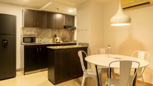 Eine moderne Küche mit dunklen Schränken, einer Arbeitsplatte aus Granit, einer eingebauten Mikrowelle und einem Essbereich mit einem weißen Tisch und Stühlen.