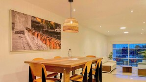 A dining area with a wooden table, chairs, a hanging light fixture, and a large framed photograph on the wall. - w*| Spectacular 2BR w/ Balcony n AC in Bocagrande (Cartagena de Indias)