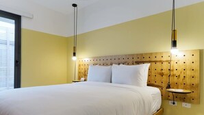 Un dormitorio con una cama grande, cabecera de madera, mesitas de noche e iluminación colgante.