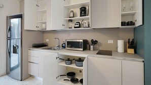 Una cocina moderna con armarios blancos, un refrigerador de acero inoxidable, un microondas y diversos utensilios de cocina.
