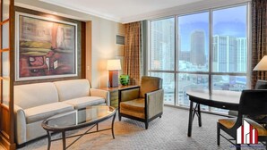 A hotel room with a large window, a sofa, a chair, a small table, and a painting on the wall. - MGM Signature- Group and Family friendly 2 units (Las Vegas)