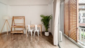 Varanda com tela de madeira, planta em vaso e mesa com duas cadeiras brancas.