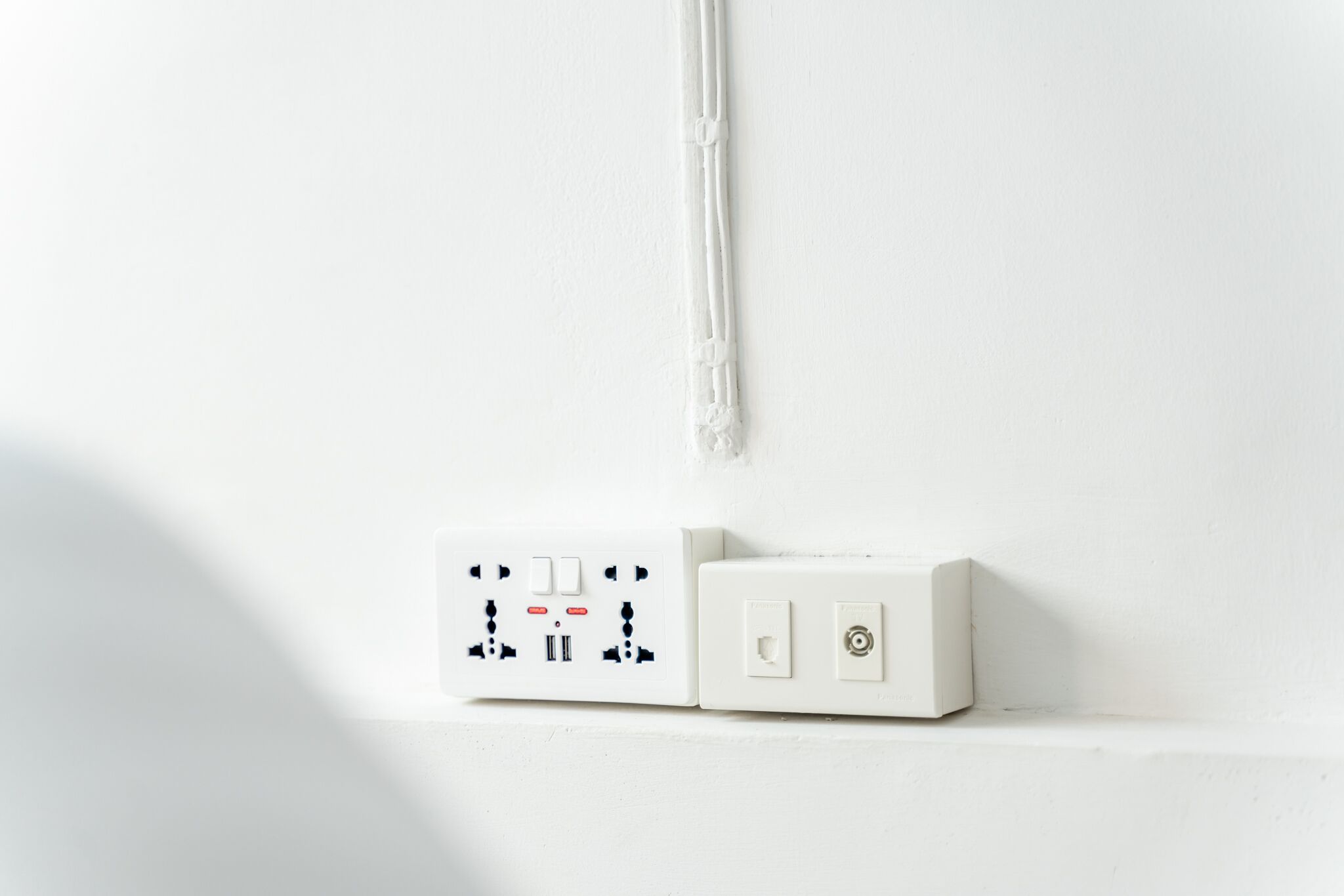 A white electrical outlet and switch on a wall.