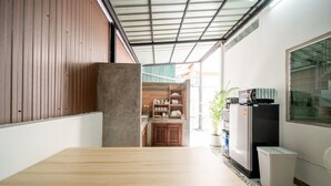 Uma cozinha compacta com uma mesa de madeira, um frigorífico e uma planta em vaso.