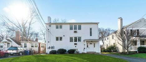 A two-story white house with a front porch, a garage, and a well-maintained lawn.