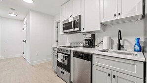 Una cucina moderna con mobili bianchi, elettrodomestici in acciaio inossidabile e una lavastoviglie.