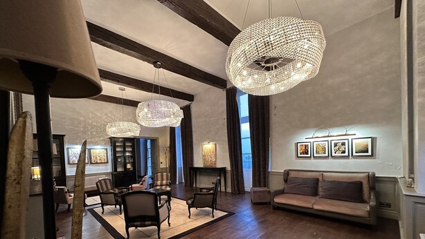 A spacious living room with a wooden floor, a sofa, a dining area with chairs, and a chandelier. - Grande Maison de Vacances (Projan)