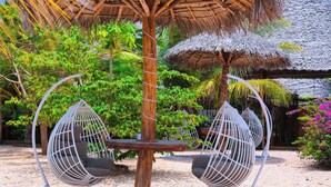 A thatched-roof structure with two white egg-shaped chairs with cushions. - Palm Cultural Village (Paje)