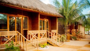 A wooden building with a thatched roof, wooden balconies, and a staircase leading to the entrance. - Palm Cultural Village (Paje)