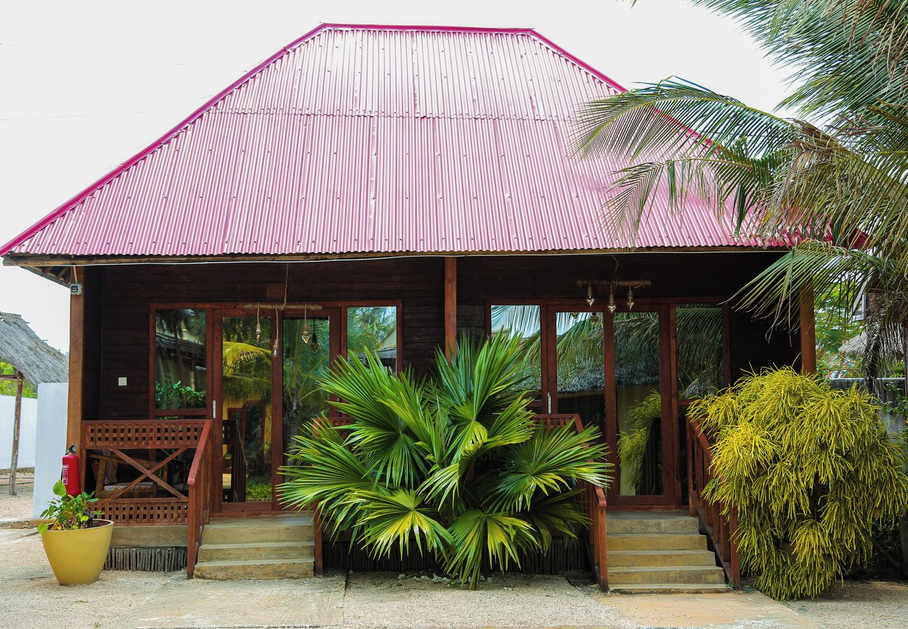 A building with a corrugated metal roof, wooden exterior, and a porch with steps leading to a door.