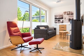 A modern living room with a red leather chair, grey sofa, and a black refrigerator. - Modern vacation apartment for 4 people in the best city location (Winterberg)