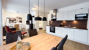 A modern kitchen with white cabinets, a wooden countertop, and black pendant lights. - Modern vacation apartment for 4 people in the best city location (Winterberg)