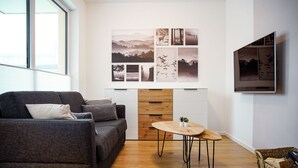 A modern living room with a grey sofa, wooden sideboard, and a small wooden table with two potted plants. - Modern vacation apartment for 4 people in the best city location (Winterberg)