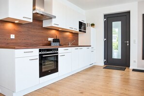 A modern kitchen with white cabinets, a built-in oven, and a coffee machine.