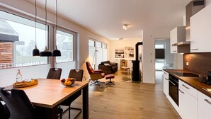 A modern kitchen with a dining area, wooden flooring, and large windows. - Modern vacation apartment for 4 people in the best city location (Winterberg)
